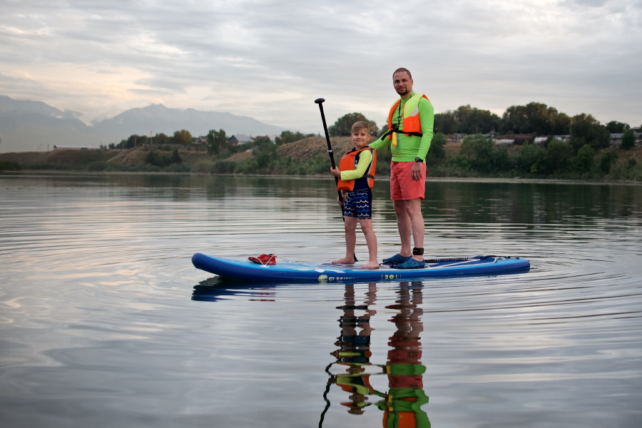 father and son having fun while stand up paddleboarding
